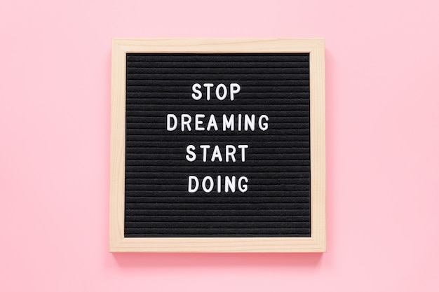 Stop Dreaming Start Doing. Motivational quote on letterboard on pink background.  Concept inspirational quote