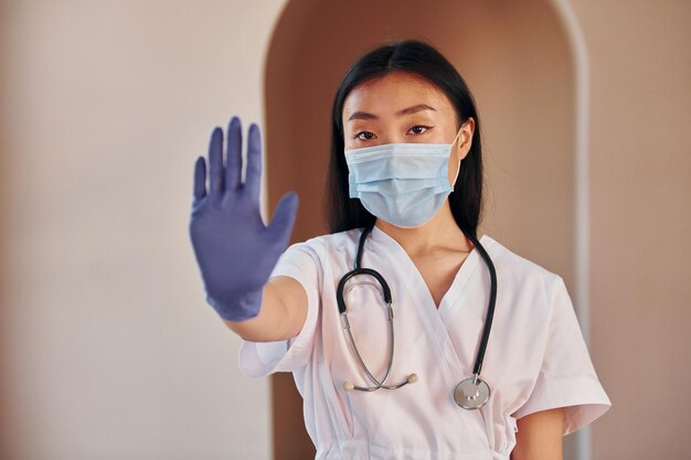 Stop gesture by hand Young serious asian woman standing indoors