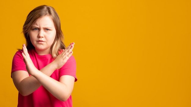 Stop gesture child protest offer rejection no answer disturbed\
young girl in pink showing x sign