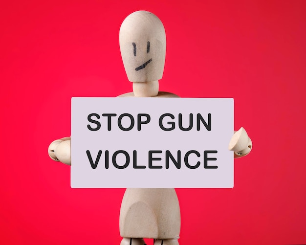 Stop gun violence the text on the card of the wooden man on a red background