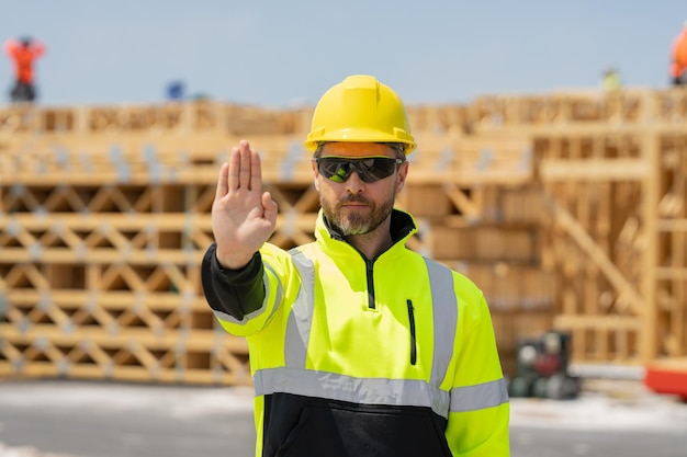 Stop hand gesture worker near american wood frame house construction american wooden house in beams