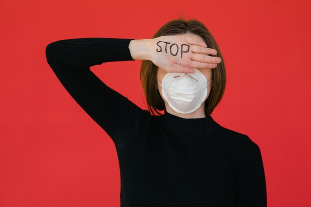 Stop het virus en de epidemische ziekten Gezonde vrouw met medisch beschermend masker met gebaar stop