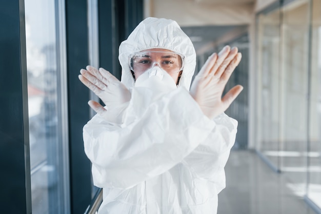 Stop het virusgebaar. Vrouwelijke arts wetenschapper in laboratoriumjas, defensieve brillen en masker permanent binnenshuis