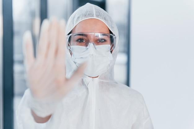 Stop het virusteken. Portret van vrouwelijke arts wetenschapper in laboratoriumjas, eyewear verdediging en masker