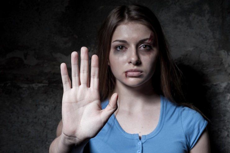 Photo stop hurting woman! young beaten up woman looking at camera and stretching out hand while standing against dark wall