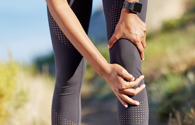 Остановитесь, если чувствуете, что ваше тело напрягается Крупный план неузнаваемой женщины, держащейся за колено от боли во время тренировки на открытом воздухе