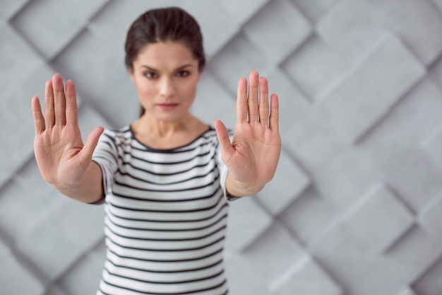 Foto stop met onrecht. aardige, aangename jonge vrouw die naar je kijkt en haar handen voor zich houdt terwijl ze stop met geweld zegt