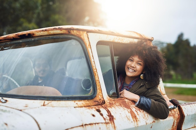 Stop nooit met verkennen. Shot van een gelukkige jonge vrouw die in een roestige oude vrachtwagen zit