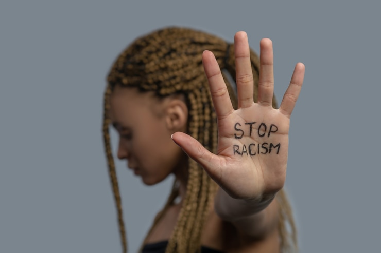 Foto stop racisme. jonge afro-amerikaanse vrouw die zijwaarts staat, hoofd naar beneden, palm met stop racisme belettering