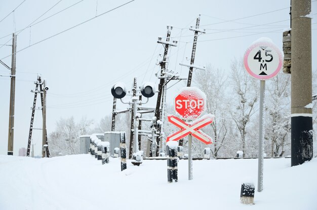 Stop. Red road sign is located on the motorway crossing the railway line in winter season