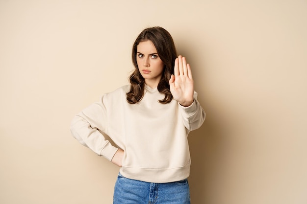 Stop serious and confident woman showing extended arm palm prohibit forbid smth blocking something s...