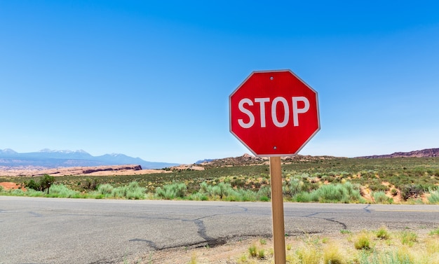 Stop sign on valley road. Blue sky on surface.