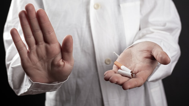 Stop smoking, a broken cigarette in the hands of a doctor.