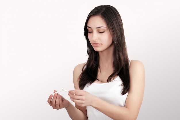 Stop Smoking Cigarettes Concept. Portrait Of Beautiful Smiling Woman Holding Broken Cigarette In Hands. Happy Female Quitting Smoking Cigarettes. Quit Bad Habit Concept.