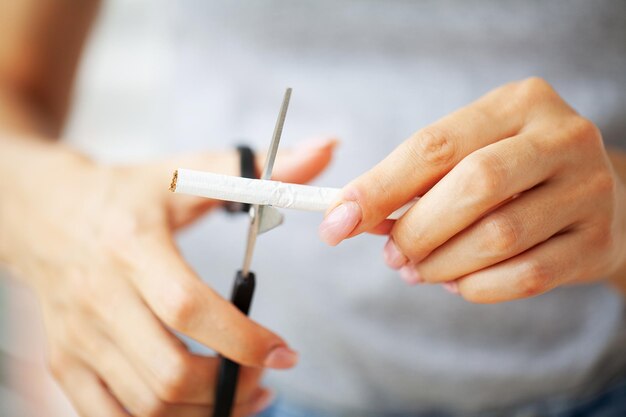 Stop smoking close up of woman cuts a cigarette with scissors