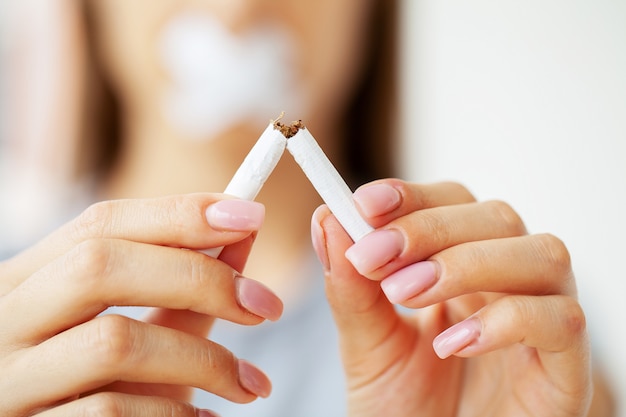 Stop smoking, close up of woman holding a broken cigarette