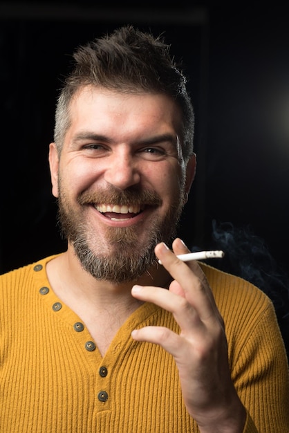 Бросьте курить, начните жить Счастливый курящий наркоман или курильщик Бородатый мужчина улыбается, куря сигарету Веселый хипстер, наслаждающийся вредными привычками курения