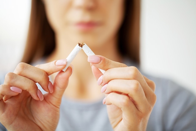 Stop smoking, woman holding a broken cigarette.