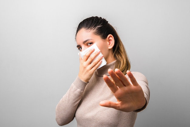 Foto smetti di diffondere coronavirus. giovane donna in possesso di un tovagliolo come una maschera di protezione antivirus e mano sollevata chiedendo di mantenere le distanze