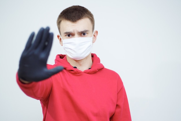 Foto smettere di diffondere covid-19. uomo con maschera e guanti che mostrano il simbolo di arresto. pandemia problema mondiale. simbolo di protezione e responsabilità.