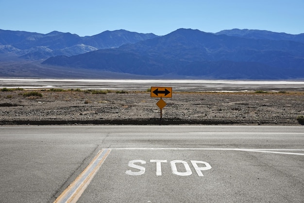 stop text on road by mountains against clear sky