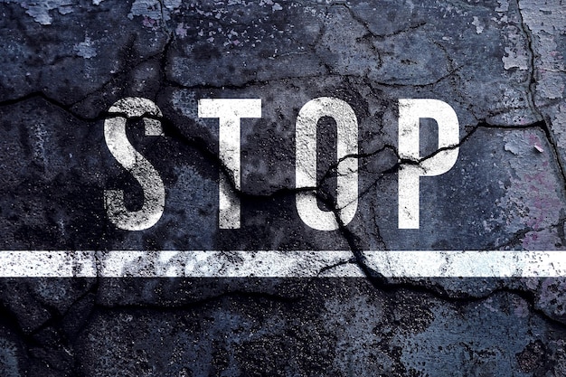 Stop text written with broken cement wall Stop word on street