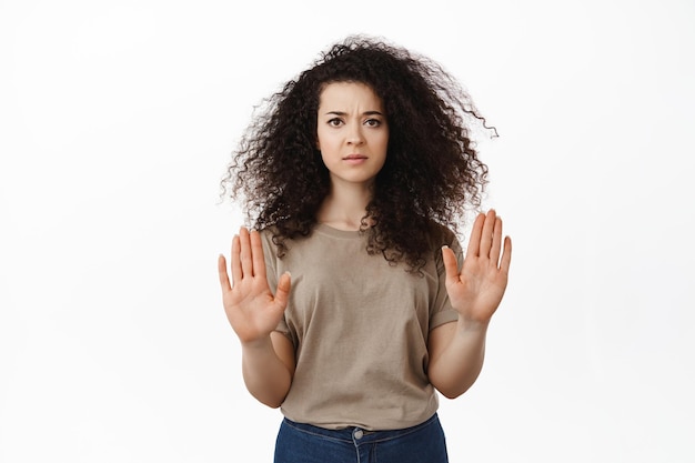 Stop this. Serious concerned woman showing no, block gesture, raising hands to disapprove and decline bad offer, rejecting you, standing against white background