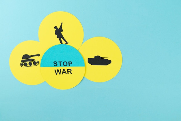 Photo stop war circles in cardboard silhouette of soldier and tanks of war with message stop war on ukranian flag copy space