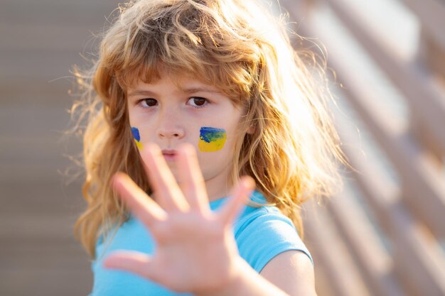 Остановить войну жестами рук украинский флаг на детской щеке маленький ребенок в знак протеста с украинским флагом k
