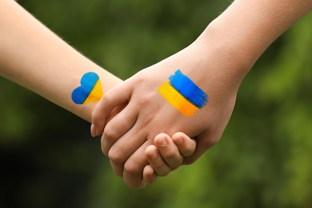 Stop war in Ukraine Mother and her child holding hands outdoors closeup Drawings with colors of Ukrainian flag