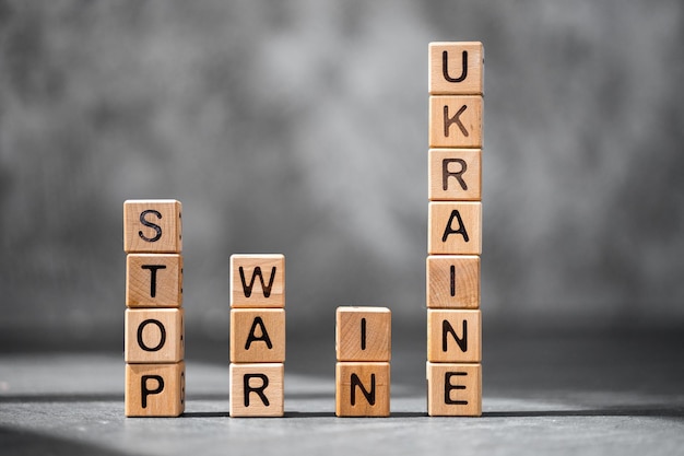 Photo stop war in ukraine word is made of wooden blocks on the dark table