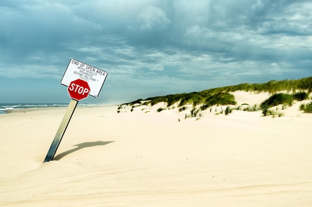 Stopbord op het strand tegen bewolkte lucht