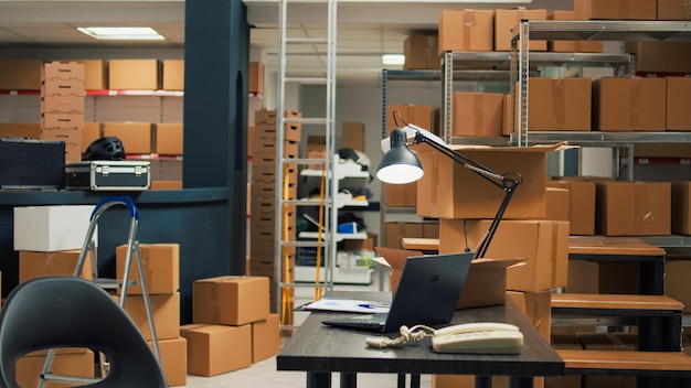 Storage room filled with merchandise packed in boxes, placed on shelves and racks in empty warehouse. Small business space used for shipping products and doing stock inventory.