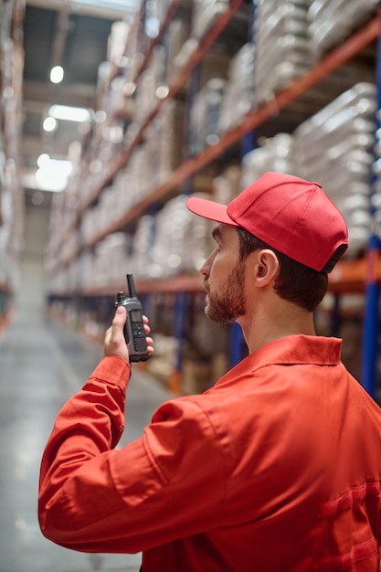 Storehouse employee communicating over the walkie-talkie in the workplace