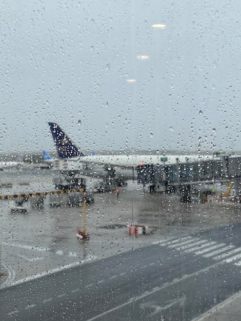 Storm at the airport before onboarding view of airplane through\
rain drops. weather delay flight