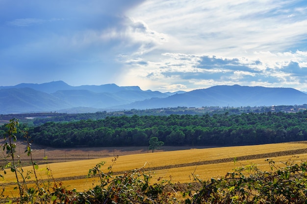 Storm clouds over the high mountains with tillage field in the foreground at sunset