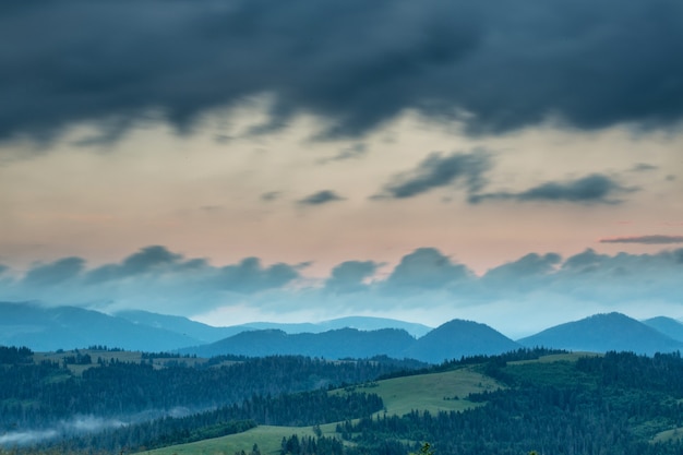 Storm clouds over the mountains and the forest during sunset.