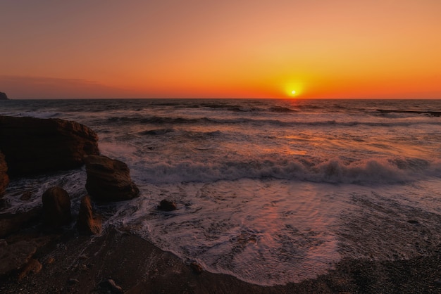 Storm op een rotsachtige zeekust bij zonsondergang