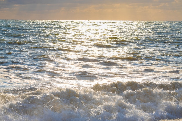 Tempesta sul mare nei raggi delle grandi onde del tramonto, spray.