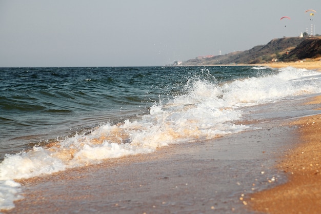 Stormachtige zee achtergrond. golven en spatten. zandstrand.