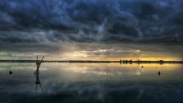Stormwolken die zich tijdens de zonsondergang in de zee weerspiegelen