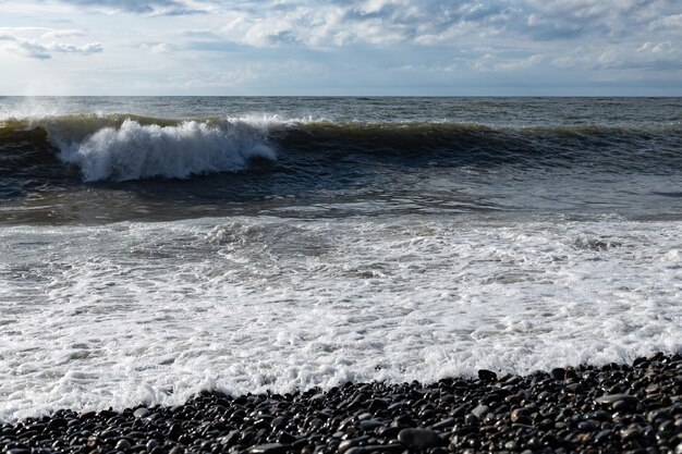 Stormy gray sea strong waves crashing on the rocky beach