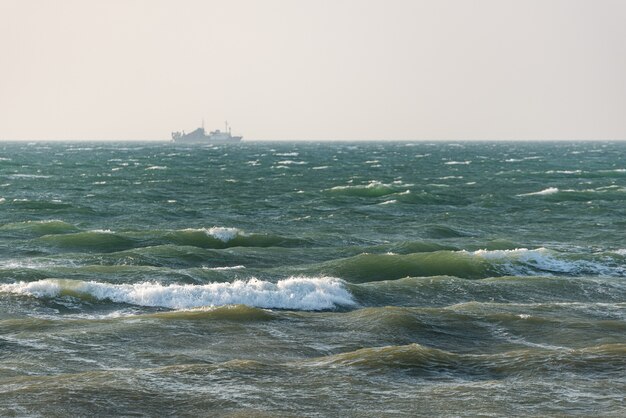 Stormy sea and ship away in the haze