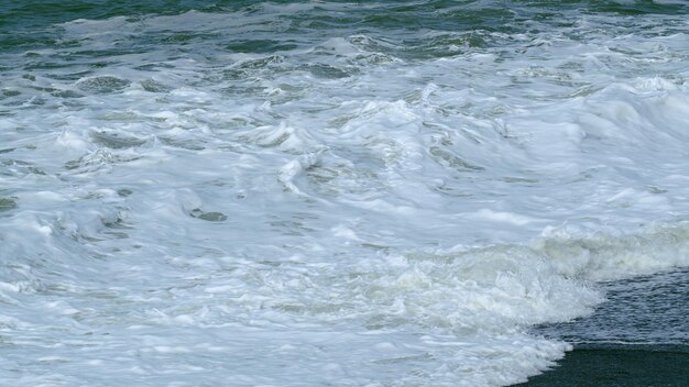 Stormy seascape blue water of ocean crashing breaking surf with foam in ocean slow motion