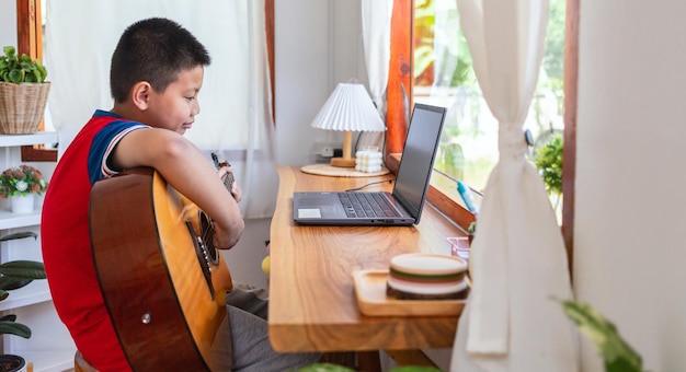 The story of a boy watching a notebook computer while preparing to practice playing guitar at home