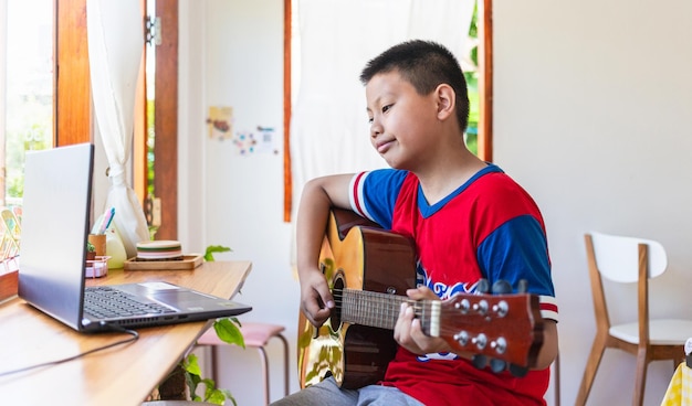 The story of a boy watching a notebook computer while preparing to practice playing guitar at home