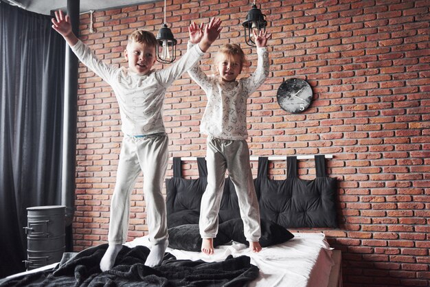 Stoute kinderen Kleine jongen en meisje voerden een kussengevecht op het bed in de slaapkamer. Ze houden van dat soort spel