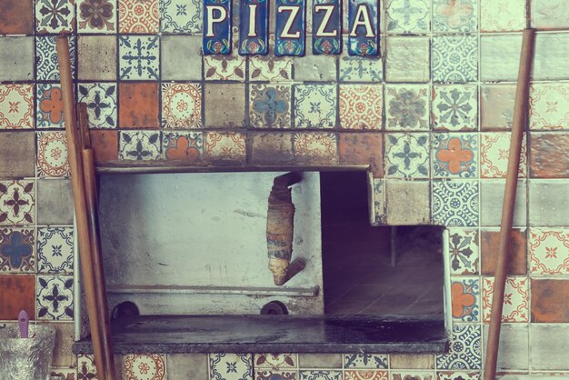 Stove decorated ceramic tiles with oriental ornaments and the inscription PIZZA Toned