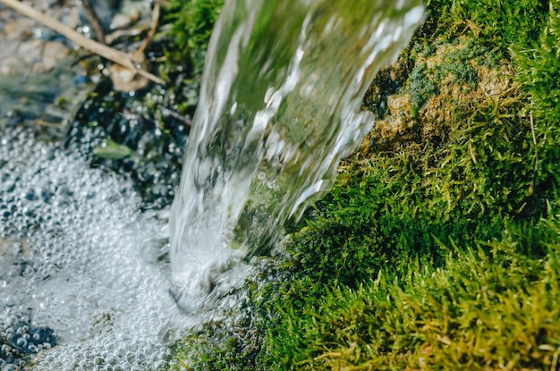 Straal water uit een bron op een achtergrond van groen mosgras schoon water ecologie