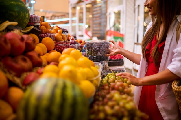 Straat fruit winkel. Een jonge vrouw die fruit kiest in een straatwinkel